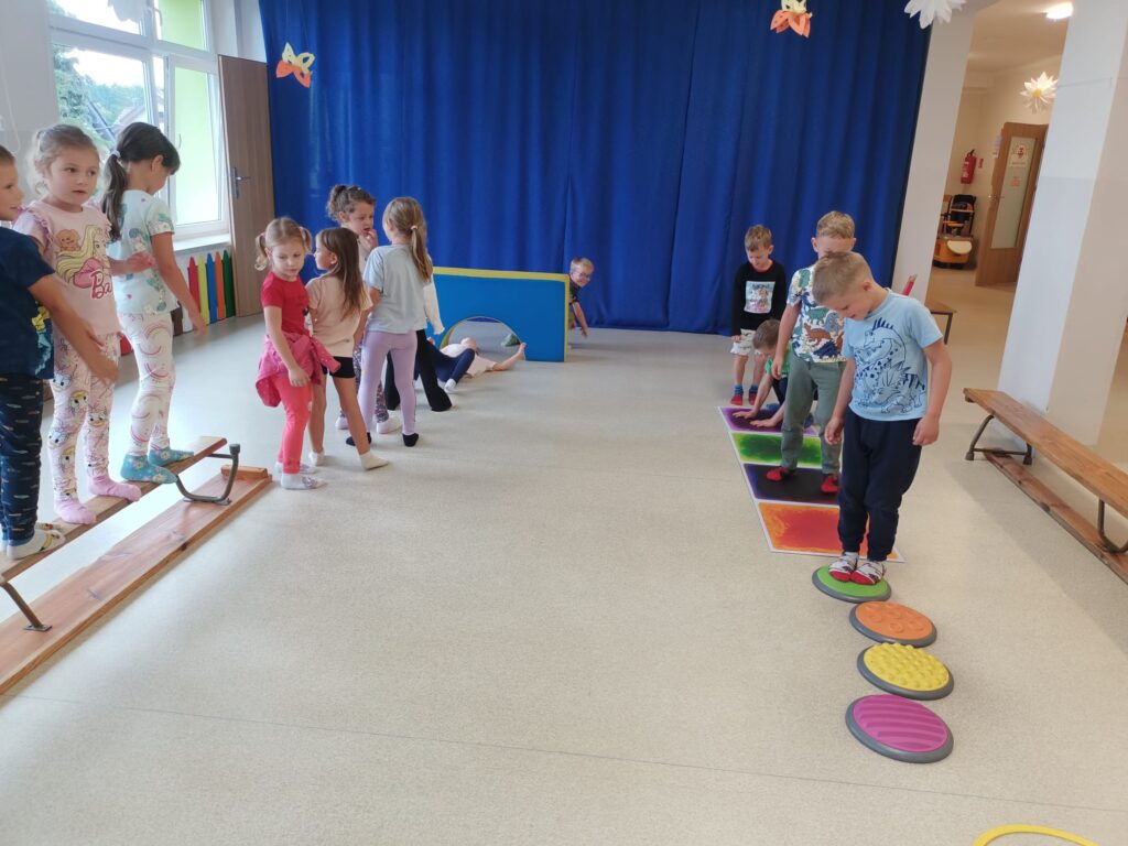 Dzieci ćwiczą na sali gimnastycznej pokonują tor przeszkód