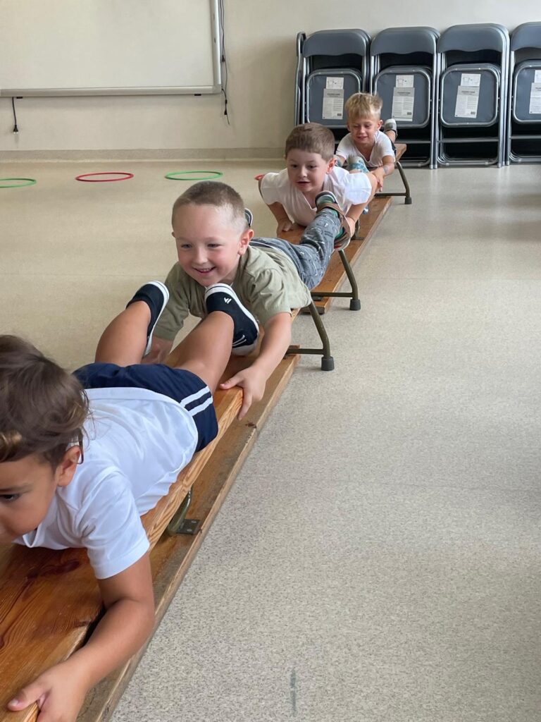 Dzieci ćwiczą na sali gimnastycznej podciągają się