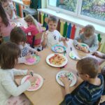 Dzieci tworzą kolorowe prace plastyczne, wykorzystując różne kształty makaronu