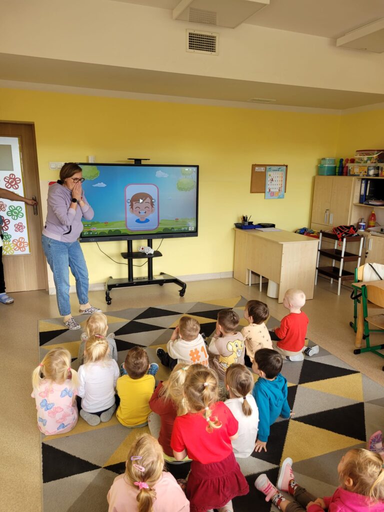 Dzieci wykonują ćwiczenia przy tablicy multimedialnej