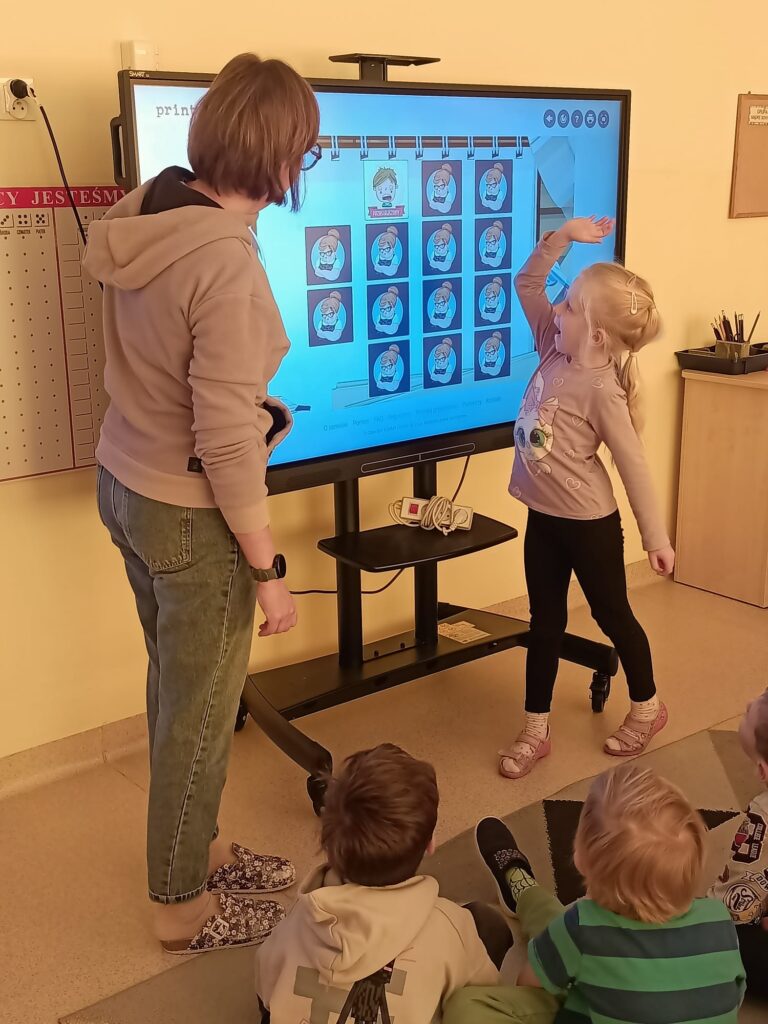 Dzieci wykonują ćwiczenia przy tablicy multimedialnej
