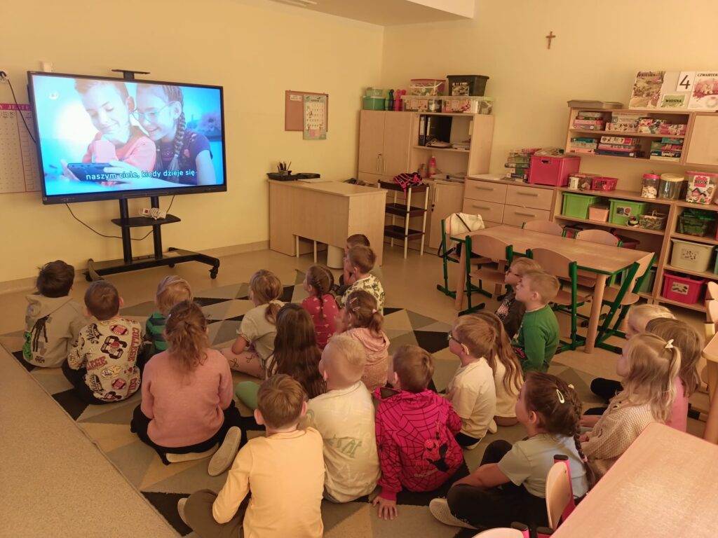 Dzieci oglądają film na tablicy multimedialnej