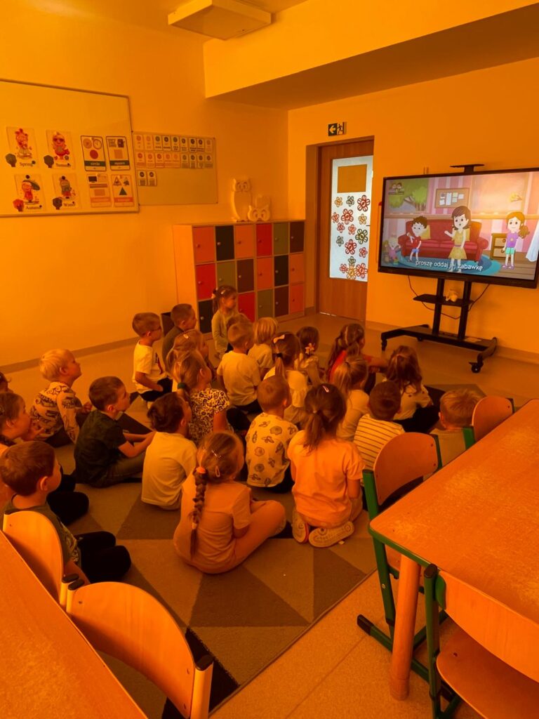 Dzieci oglądają film na tablicy multimedialnej