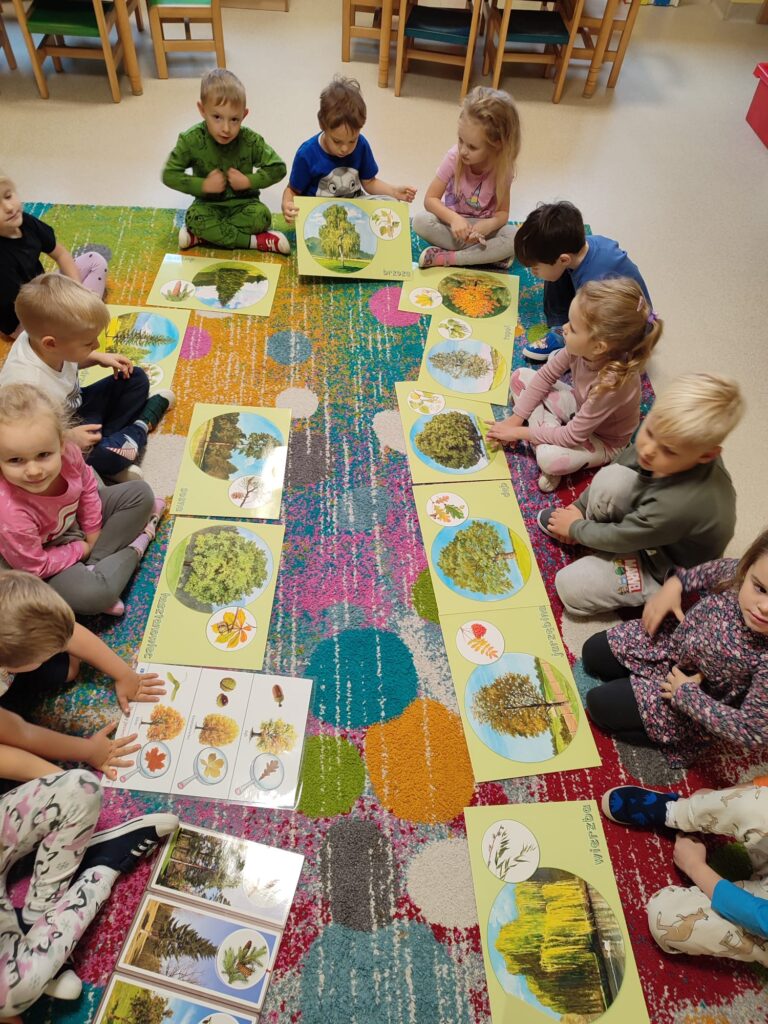 Dzieci oglądają zdjęcia różnych drzew.