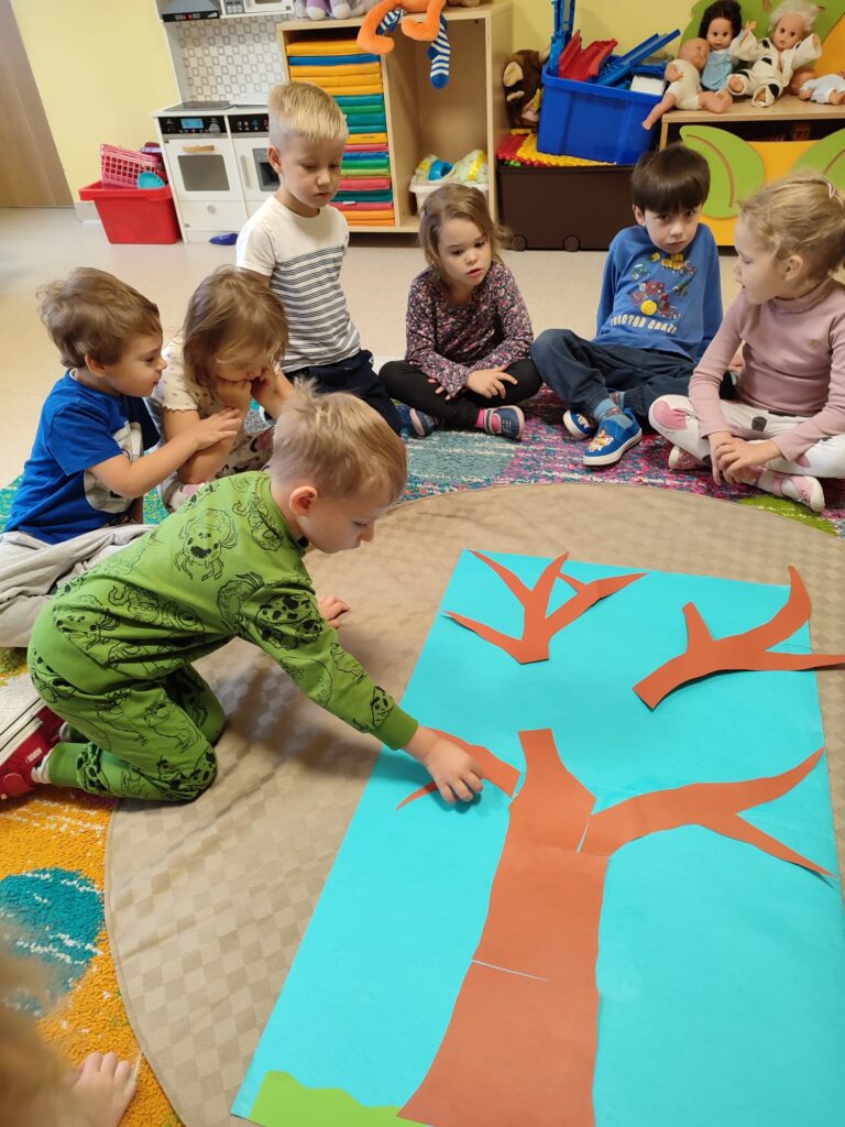 Dzieci tworzą sylwetę drzewa.