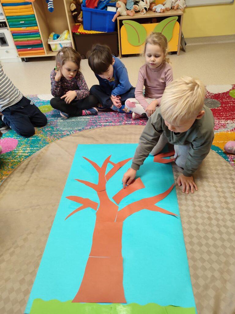 Dzieci tworzą sylwetę drzewa.