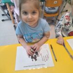 Dziecko porównuje swoją dłoń z łapą wilka