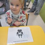 Dziecko porównuje swoją dłoń z łapą wilka