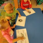 Dziecko porównuje swoją dłoń z łapą wilka