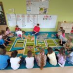 Dzieci układają papierowe kredki z literami w kolejności alfabetu