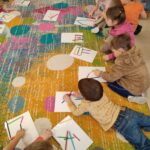 Dzieci układają z kredek różne kształty, tworząc proste kompozycje