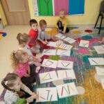 Dzieci układają z kredek różne kształty, tworząc proste kompozycje