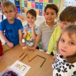 Dzieci układają z kredek różne kształty, tworząc proste kompozycje