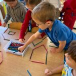 Dzieci układają z kredek różne kształty, tworząc proste kompozycje