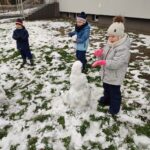 Dzieci lepią ze śniegu bałwana