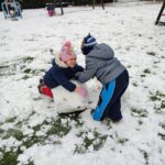 Dzieci lepią ze śniegu bałwana