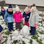 Dzieci lepią ze śniegu bałwana