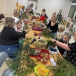 Rodzice wraz z dziećmi wykonują wieńce bożonarodzeniowe