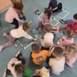 Dzieci tworzą napis LEGO z klocków
