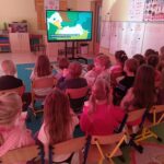 Dzieci z grupy Mądre Sowy delektują się popcornem oglądając bajkę