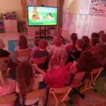 Dzieci z grupy Mądre Sowy delektują się popcornem oglądając bajkę