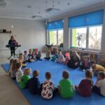 Dzieci z grupy Pszczółki uważnie słuchają opowieści dotyczącej kolejnej muzyczno-ruchowej zabawy