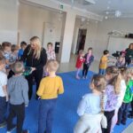 Dzieci przygotowują się do zabawy muzyczno-ruchowej zabierając grzechotkę