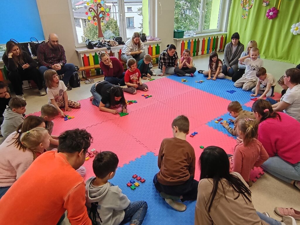 Dzieci wraz z rodzicami biorą udział w matematycznych zajęciach otwartych.
