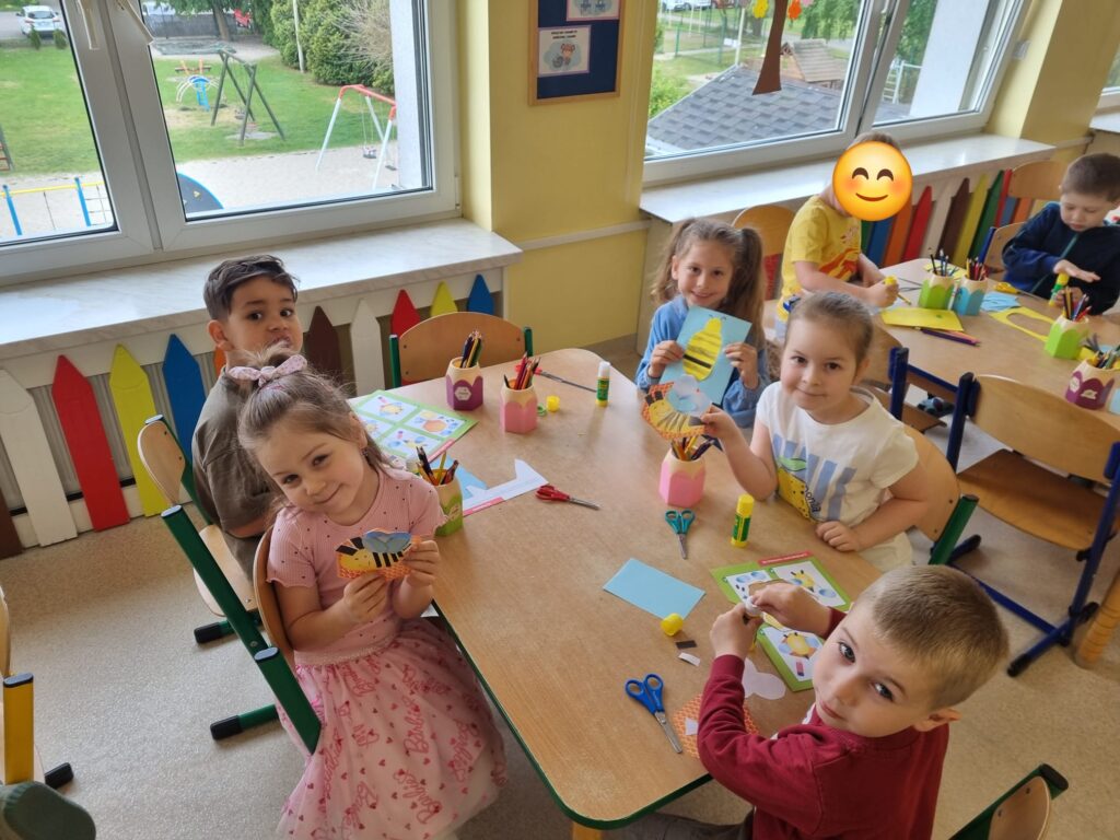Dzieci siedzą przy stolikach i wykonują prace plastczyną.