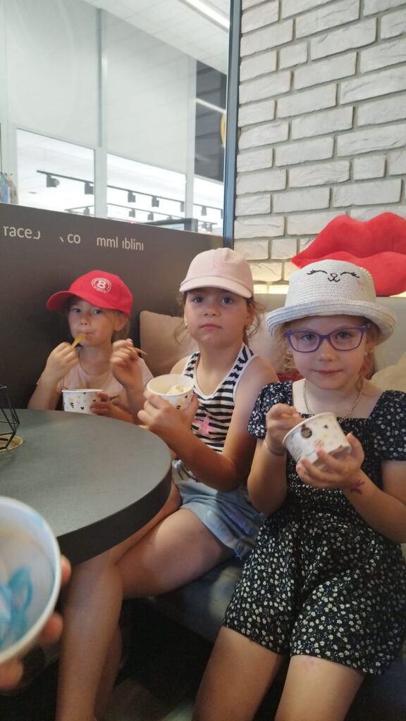 Dzieci odwiedziły kawiarnie jedzą lody.